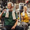 Senior man drinking water and taking a break from his workout at the gym